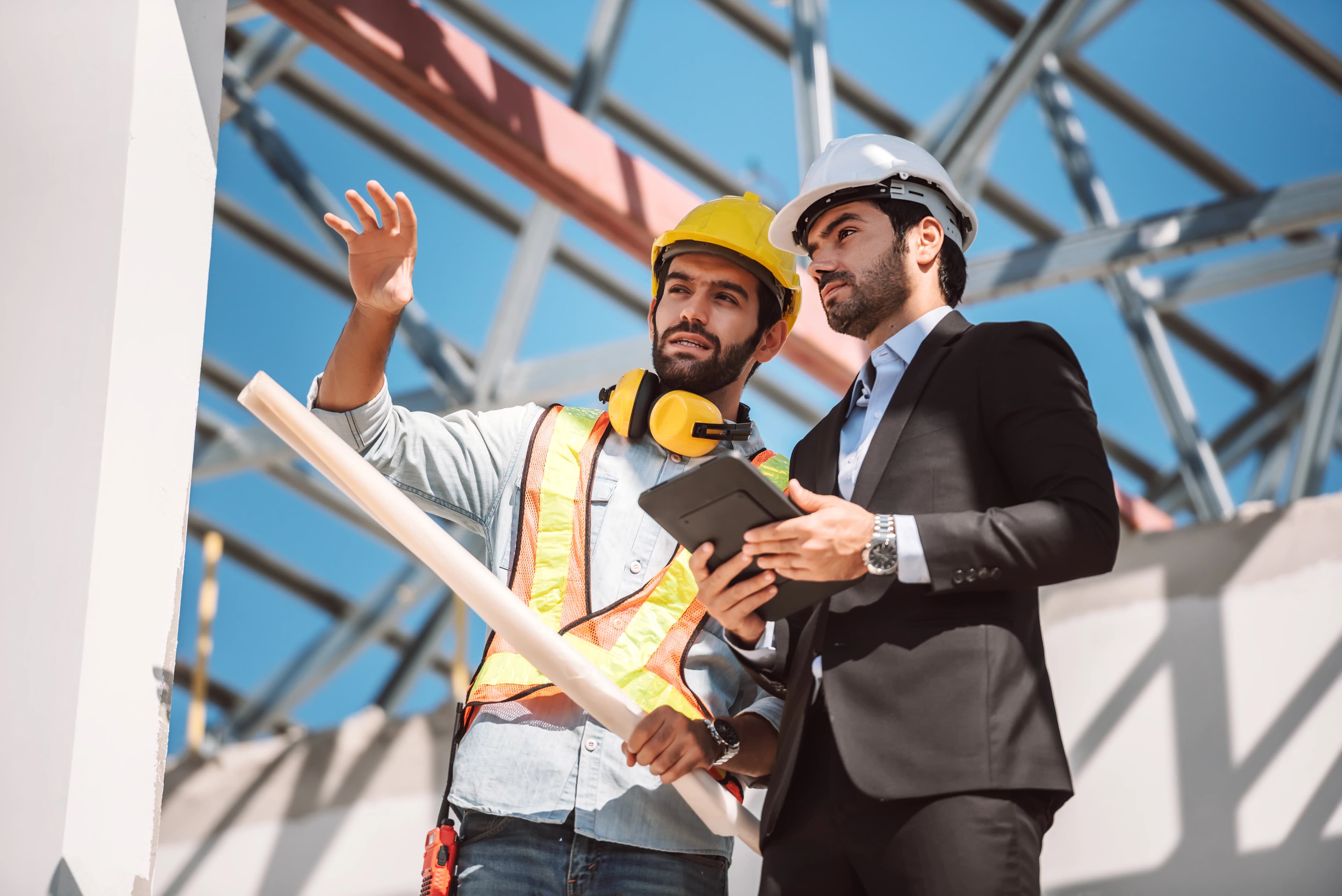 Team of civil engineers reviewing structural plans on an active construction site